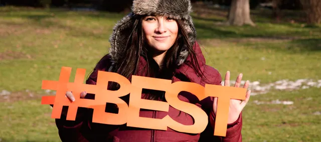Participante sosteniendo las letras naranjas de BEST en una actividad al aire libre